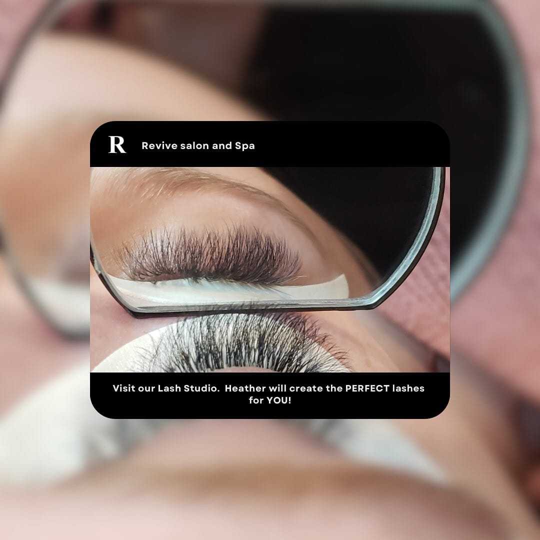 Close-up of a person getting eyelash extensions at Revive Salon and Spa with a magnifying mirror.