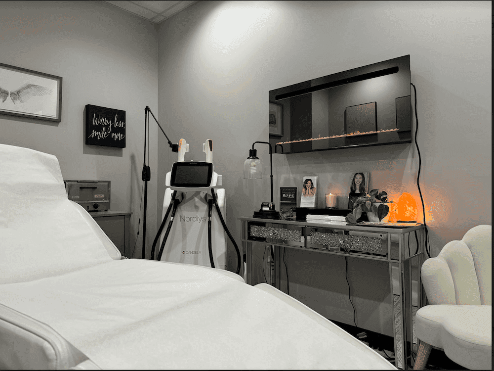 A cozy spa room featuring a treatment chair, advanced skincare equipment, and relaxing decor.
