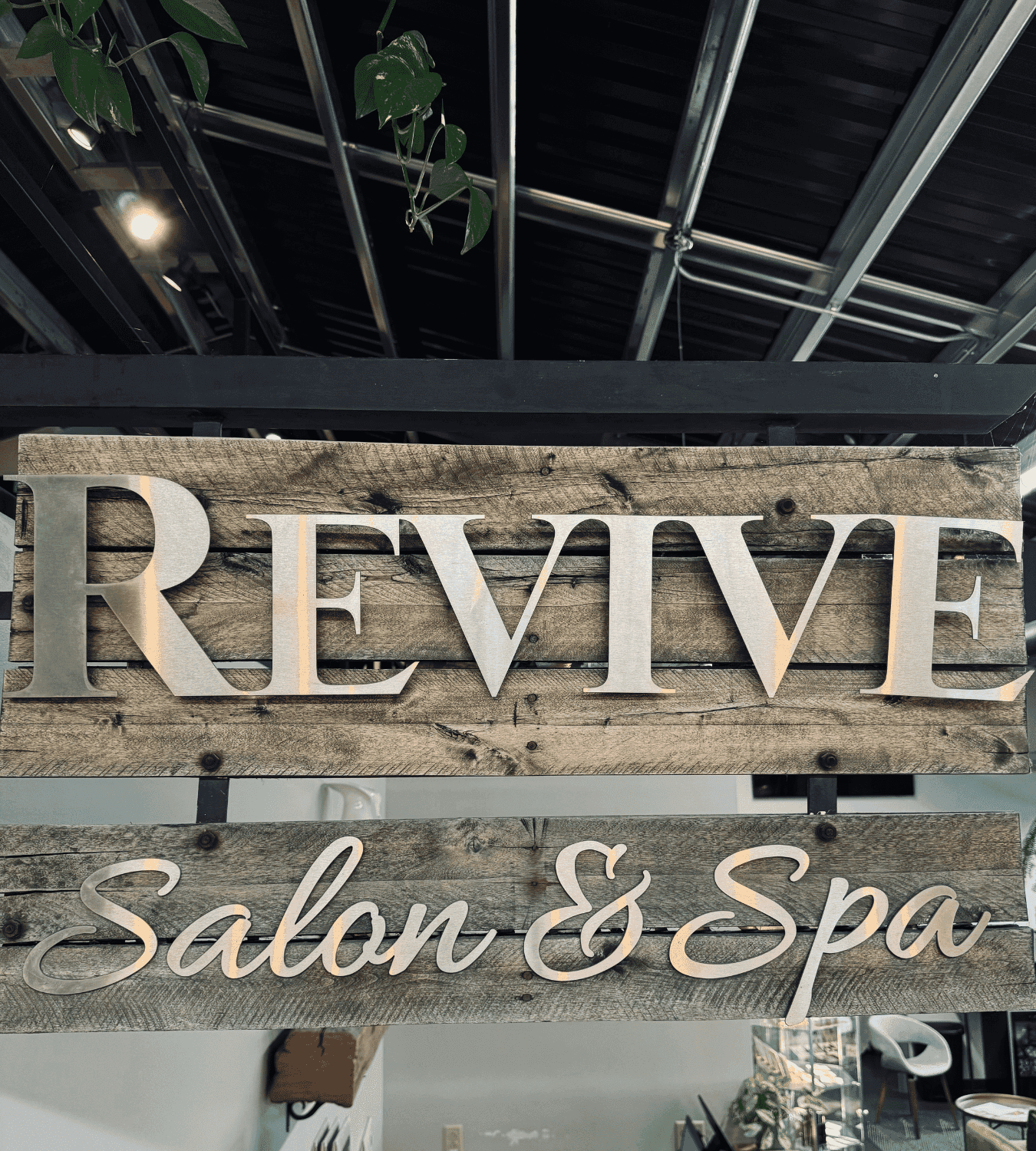 Sign reading "Revive Salon & Spa" with plants and industrial ceiling visible in the background.