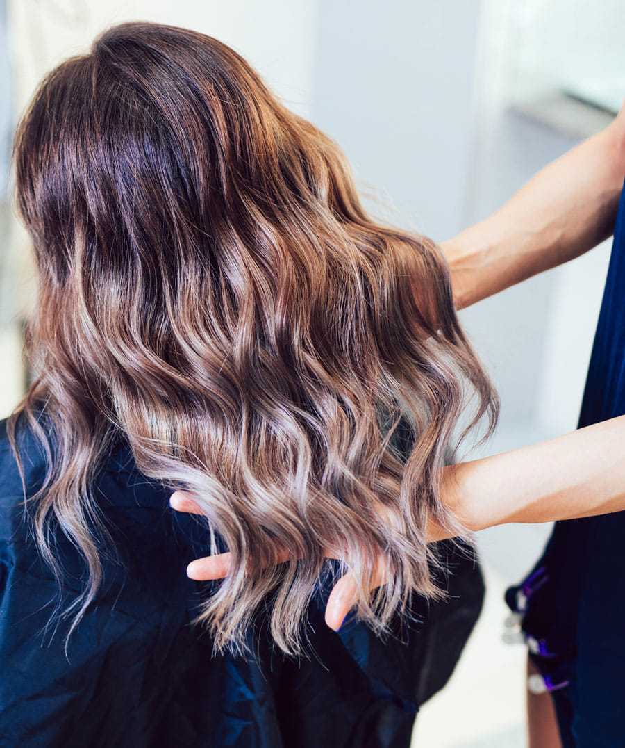 Woman's hair being styled at a salon, showcasing ombre coloring.