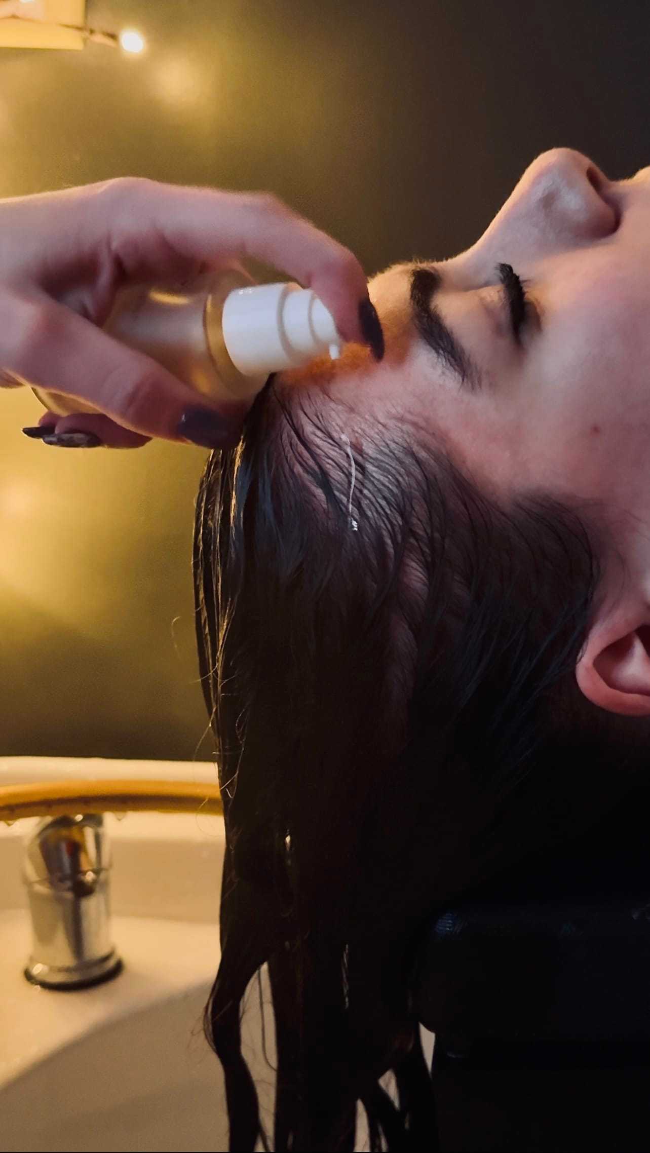 Applying hair serum to a person's scalp at a salon.