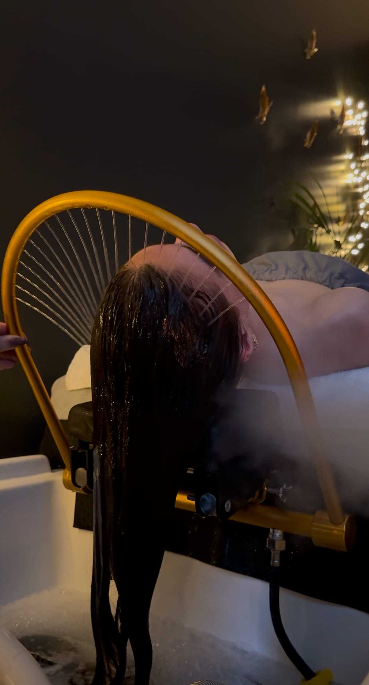 Person experiencing a relaxing hair spa treatment with water rinsing through specialized equipment.