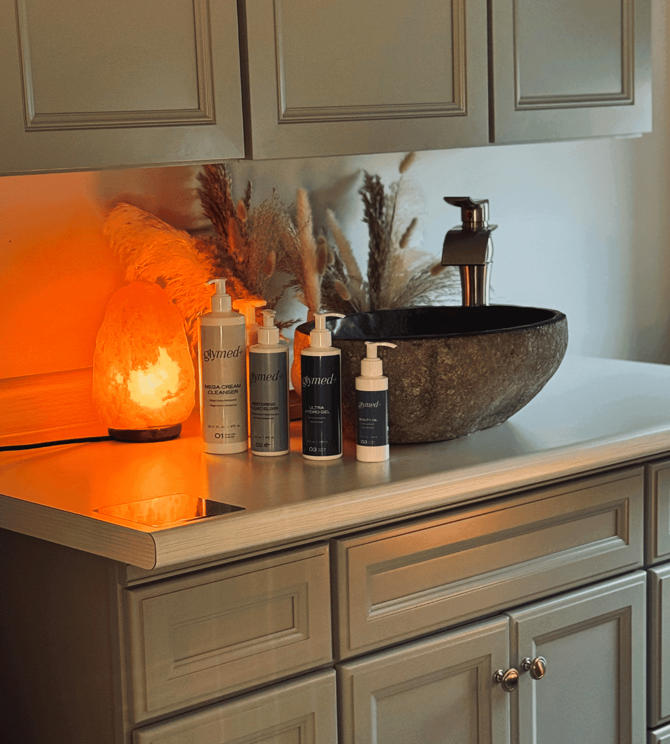 Elegant bathroom vanity with skincare products, stone sink, and Himalayan salt lamp.